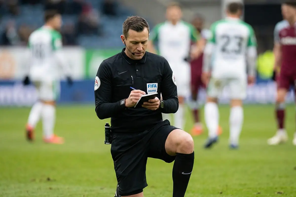 Árbitro de futebol a consultar as suas notas durante um jogo