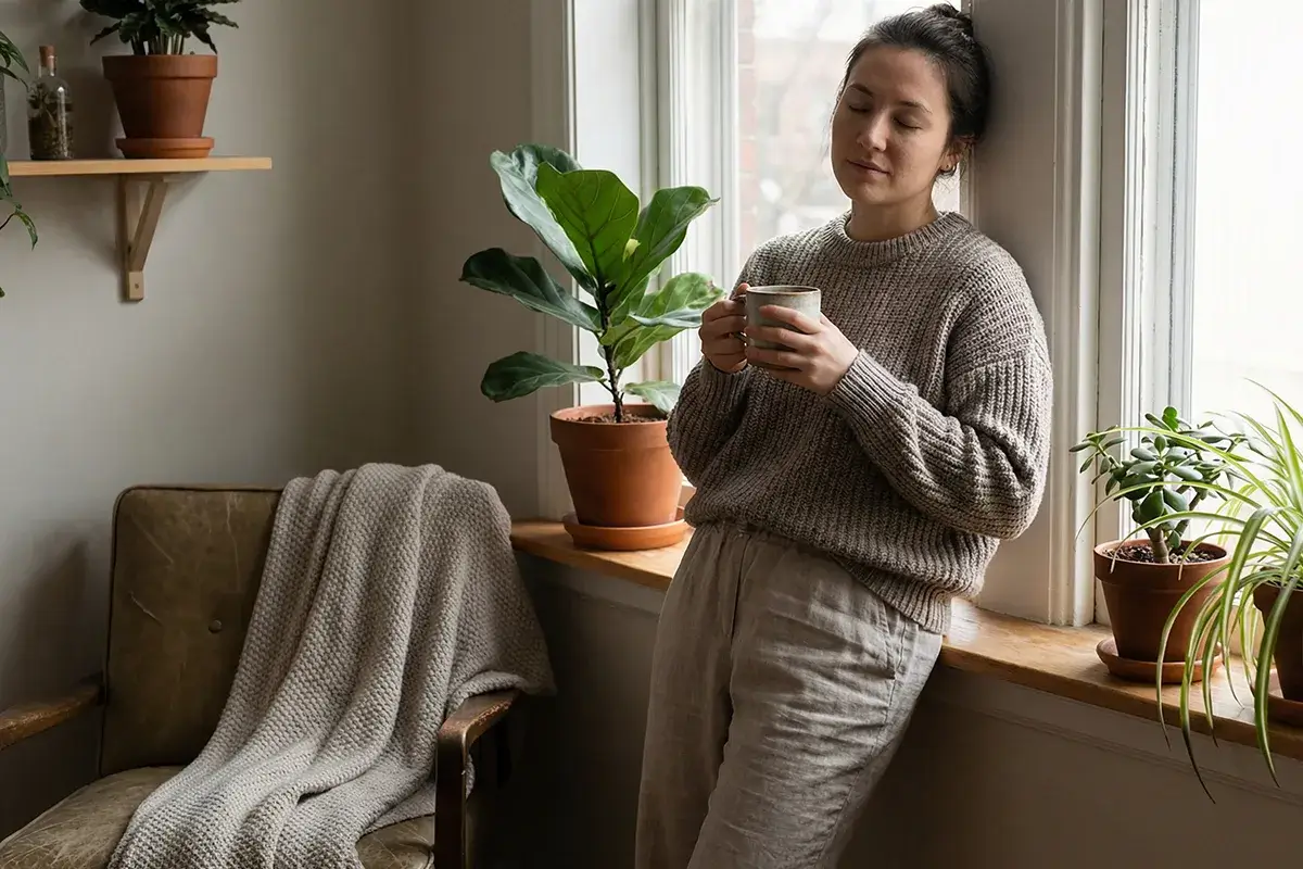 Pessoa a fazer uma pausa com uma ch&aacute;vena de caf&eacute; junto &agrave; janela