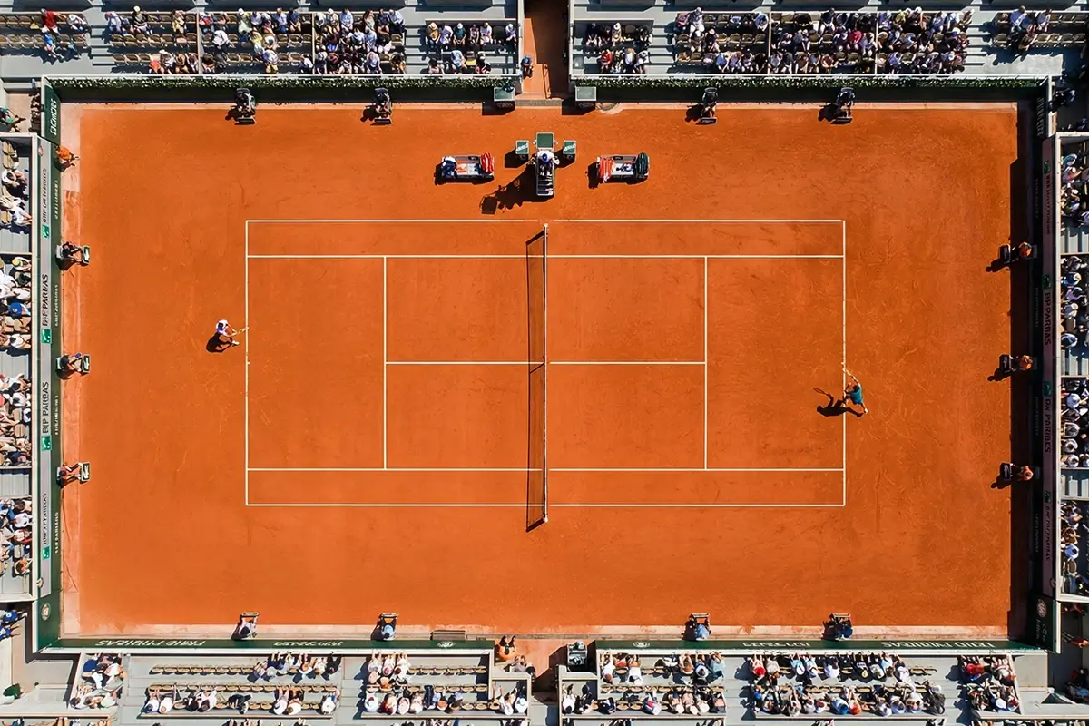 Vista a&eacute;rea de um court de t&eacute;nis de terra batida durante um torneio